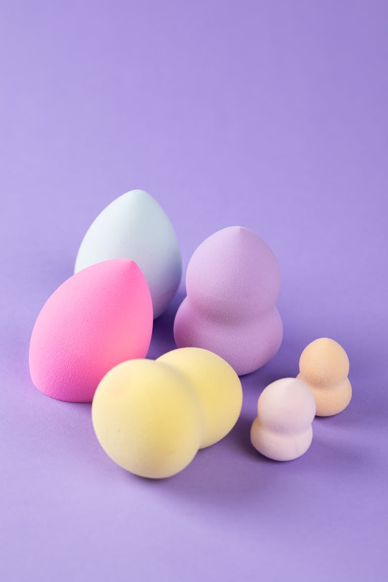 Vibrant beauty blenders and sponges on a purple backdrop for makeup lovers.