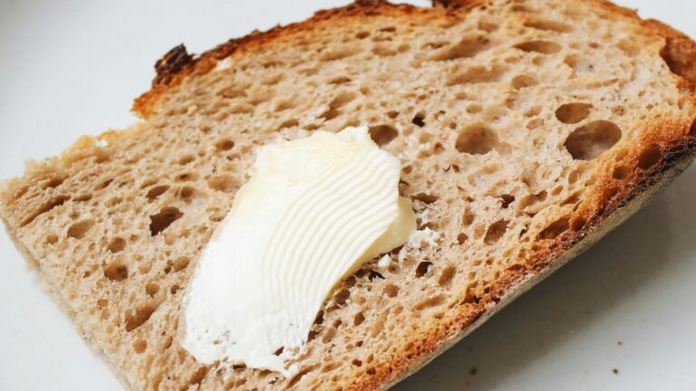 A detailed view of a buttered sourdough slice on a plate, perfect for breakfast.