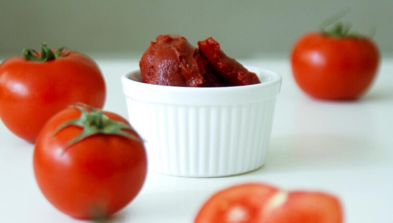 A vibrant arrangement of fresh tomatoes and tomato paste on a white background.