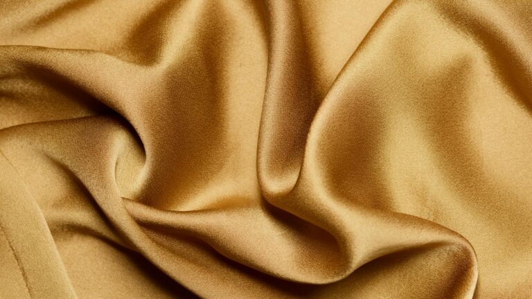 Luxurious close-up of gold silk fabric with elegant folds and texture.