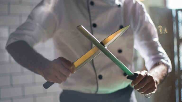Close-up of a chef sharpening knives, emphasizing culinary skill and precision.