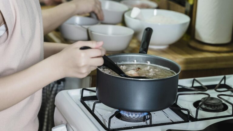 Kobieta mieszająca zupę na kuchence gazowej