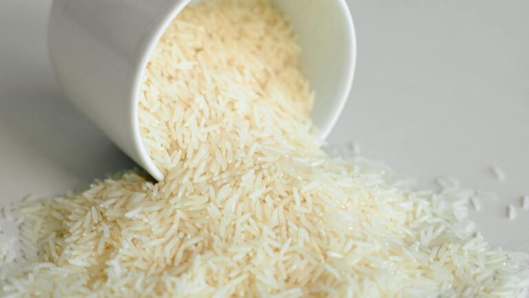 Biały nieugotowany ryż wysypujący się z naczynia na blat