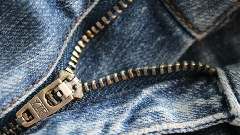 Srebrny metalowy zamek błyskawiczny w spodniach jeansowych