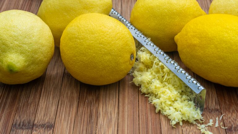 Cytryny oraz starta skórka z cytryny na drewnianej desce