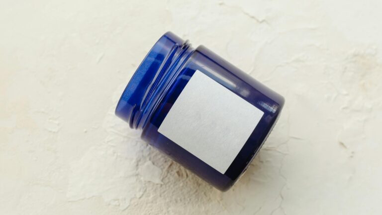 Simple blue container with label on a textured white background, perfect for mock-ups or product presentations.
