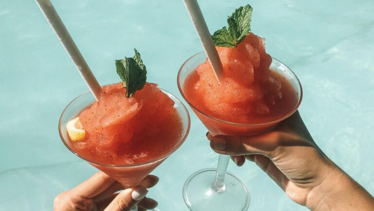 Dwa owocowe mrożone napoje trzymane nad basenem