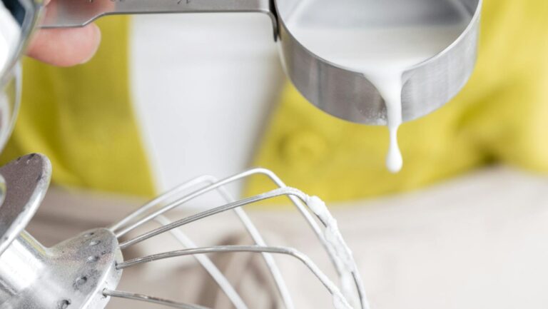 Kobieta dolewająca śmietanki do miski z mikserem
