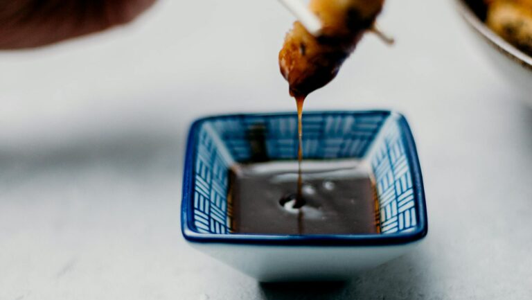 Zbliżenie na zanurzanie jedzenia w sosie sojowym za pomocą pałeczek