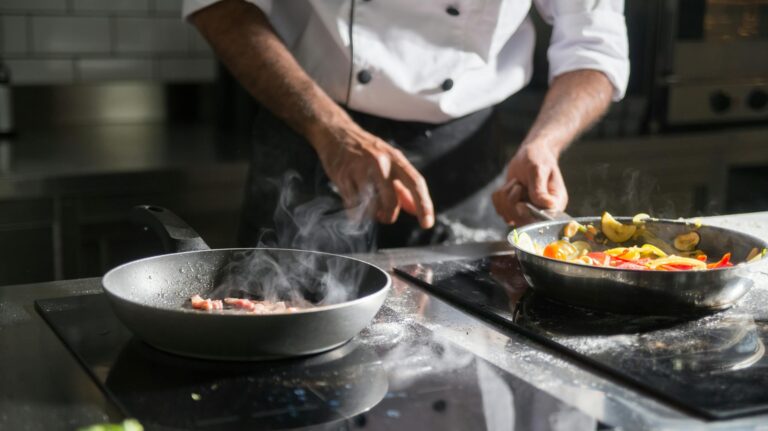 Kucharz przygotowujący danie, smażąc je na płycie indukcyjnej