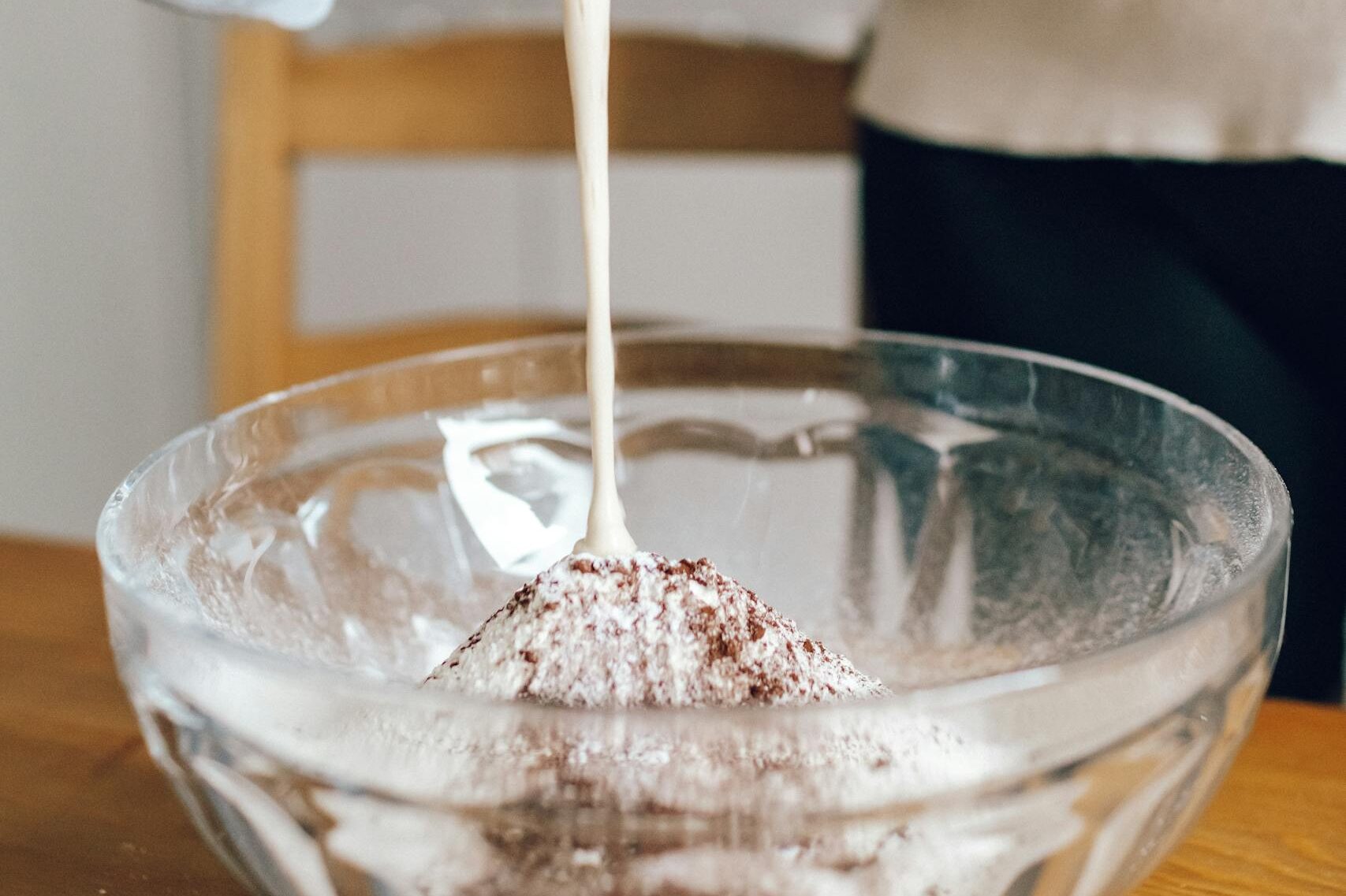 Kobieta dodająca mokre składniki ciasta do miski z suchymi 