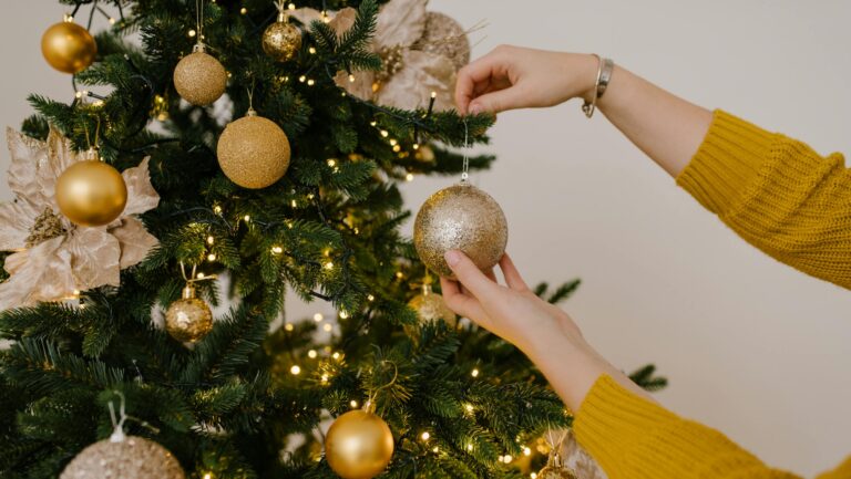 Kobieta zdejmująca złotą bombkę z choinki