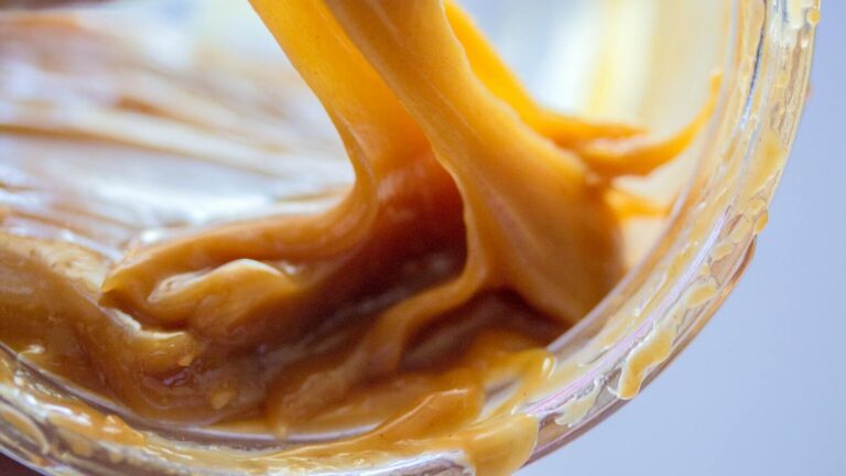 Zbliżenie na gęsty, ciągnący się karmel w słoiczku