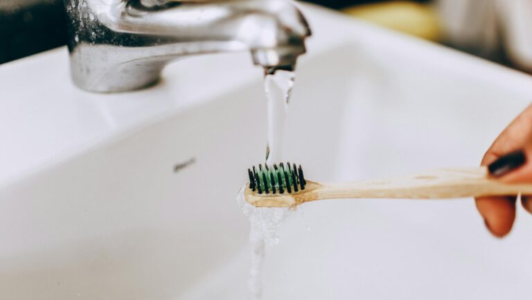Końcówka bambusowej szczoteczki do zębów zanurzona pod strumieniem wody