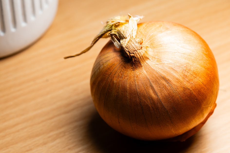 Pojedyncza świeża cebula w łupince na kuchennym blacie